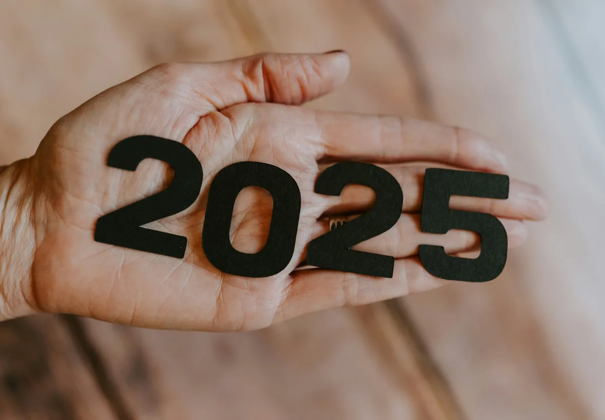 A hand holding cutout numbers spelling 2025